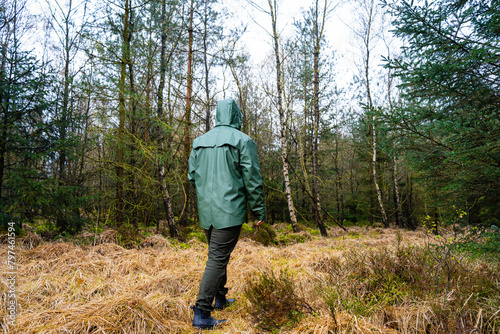 Man in green raincoat walking in the forest