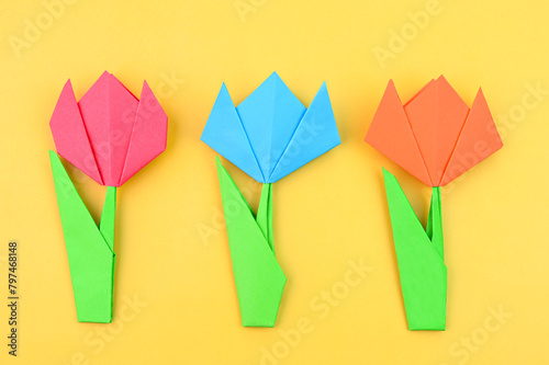 Bright origami tulip flowers on a yellow background.