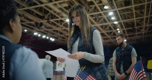 Polling officer consults voters and gives them bulletins. American citizens come to vote in polling station. National Election Day in the United States. Political races of US presidential candidates. photo