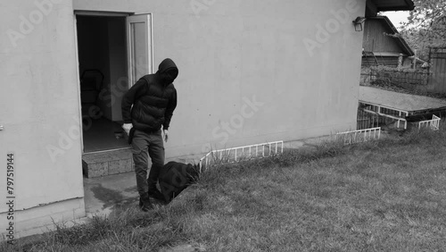 A thief or robber leaves the house with a bag of loot, captured on a CCTV camera, photo