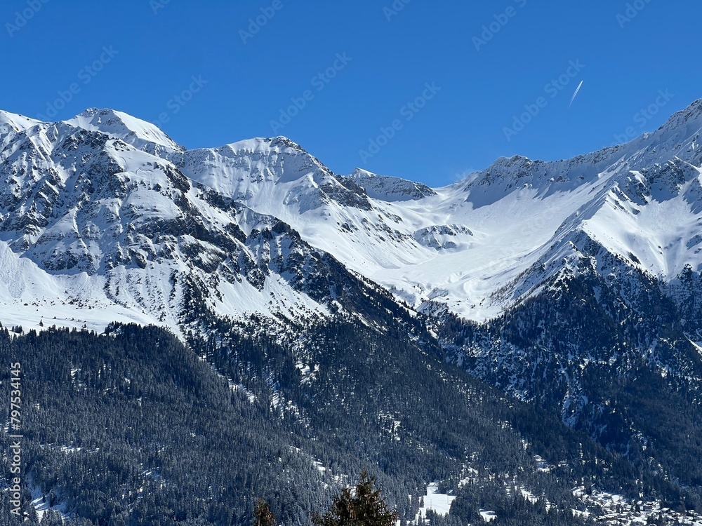 Beautiful sunlight and snow-capped alpine peaks above the Swiss tourist sports-recreational winter resorts of Valbella and Lenzerheide in the Swiss Alps - Canton of Grisons, Switzerland (Schweiz)