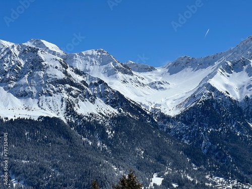Beautiful sunlight and snow-capped alpine peaks above the Swiss tourist sports-recreational winter resorts of Valbella and Lenzerheide in the Swiss Alps - Canton of Grisons  Switzerland  Schweiz 
