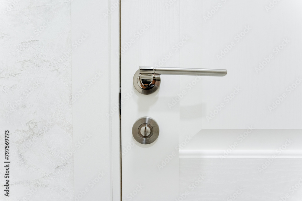 Silver door handle, furniture hardware, door locking mechanism, closed door to the room. Silver door handle, furniture hardware, door locking mechanism, closed door to the room.