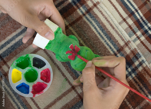 shot of Teenage girl's hand Using paintbrush for artwork, painting plaster statue.