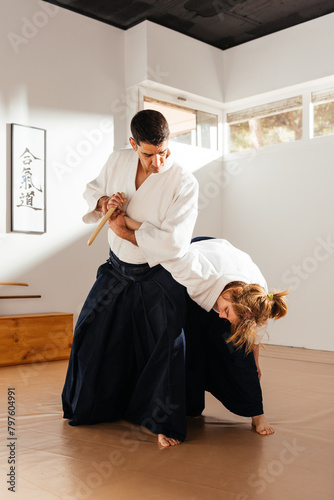 Martial Artist Demonstrating Knife Disarm With Joint Lock in Dojo photo