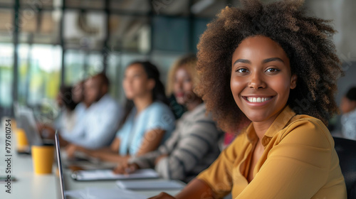 At a modern conference table, a black young woman leads a team meeting with confidence, her smile conveying both professionalism and approachability as she discusses project milest photo