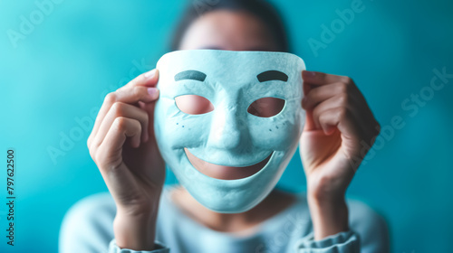 person holds up a smiling mask in front of a face