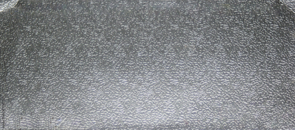 Fototapeta premium Background metal texture of a rough metal sheet with a shiny metallic surface reflecting light and stippled pattern, closeup detail