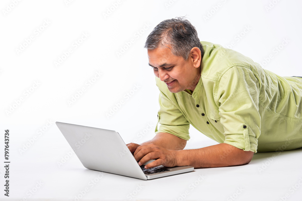 Indian asian mid age man using laptop against white background Indian asian mid age man using laptop against white background