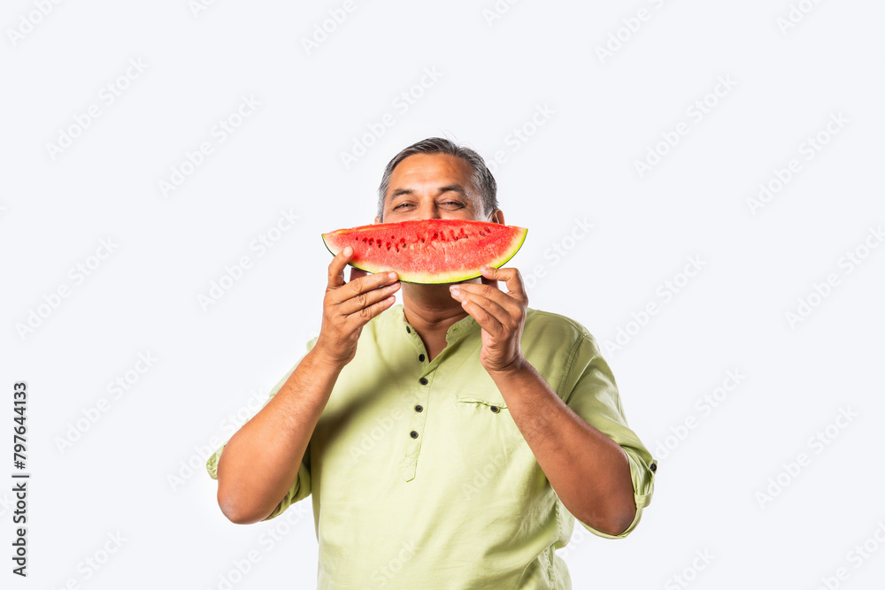Indian asian man eating watermelon slice or tarbuj at home Indian asian man eating watermelon slice or tarbuj at home