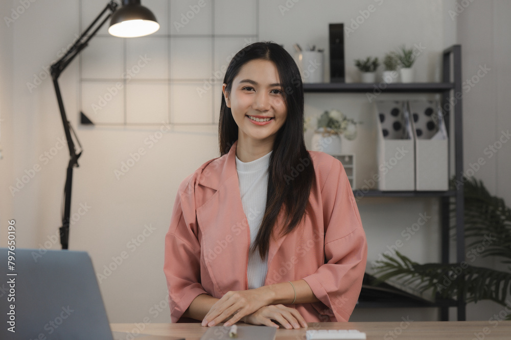 A beautiful young Asian woman is happily sitting in a private office. The atmosphere in a private office with female employees sitting in the room with smiles on their faces. A beautiful young Asian woman is happily sitting in a private office. The atmosphere in a private office with female employees sitting in the room with smiles on their faces.