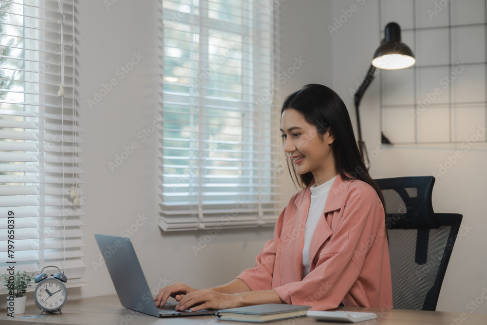 A beautiful Asian woman was happily sitting in her private office in an atmosphere filled with happiness as an assignment was being completed and completed successfully.
