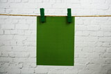 Layout of Empty paper space for text hanging on the wall with Clothespins on string against white brick wall background