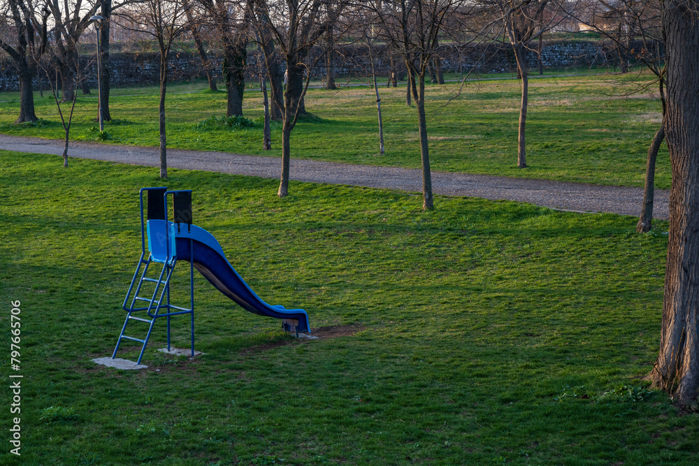 Obraz premium Blue plastic children's slide. A slide for children set in the forest in a beautiful green environment. 