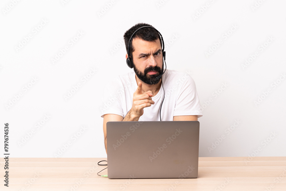 Telemarketer caucasian man working with a headset and with laptop frustrated and pointing to the front. Telemarketer caucasian man working with a headset and with laptop frustrated and pointing to the front.
