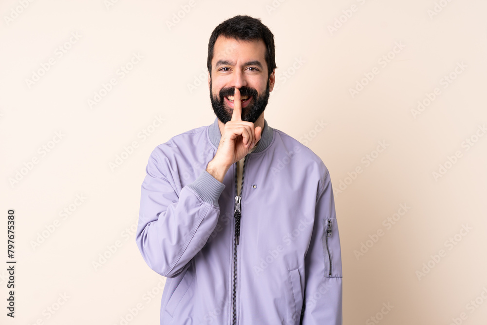 Caucasian man with beard wearing a jacket over isolated background showing a sign of silence gesture putting finger in mouth Caucasian man with beard wearing a jacket over isolated background showing a sign of silence gesture putting finger in mouth