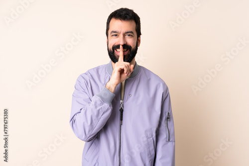 Caucasian man with beard wearing a jacket over isolated background showing a sign of silence gesture putting finger in mouth