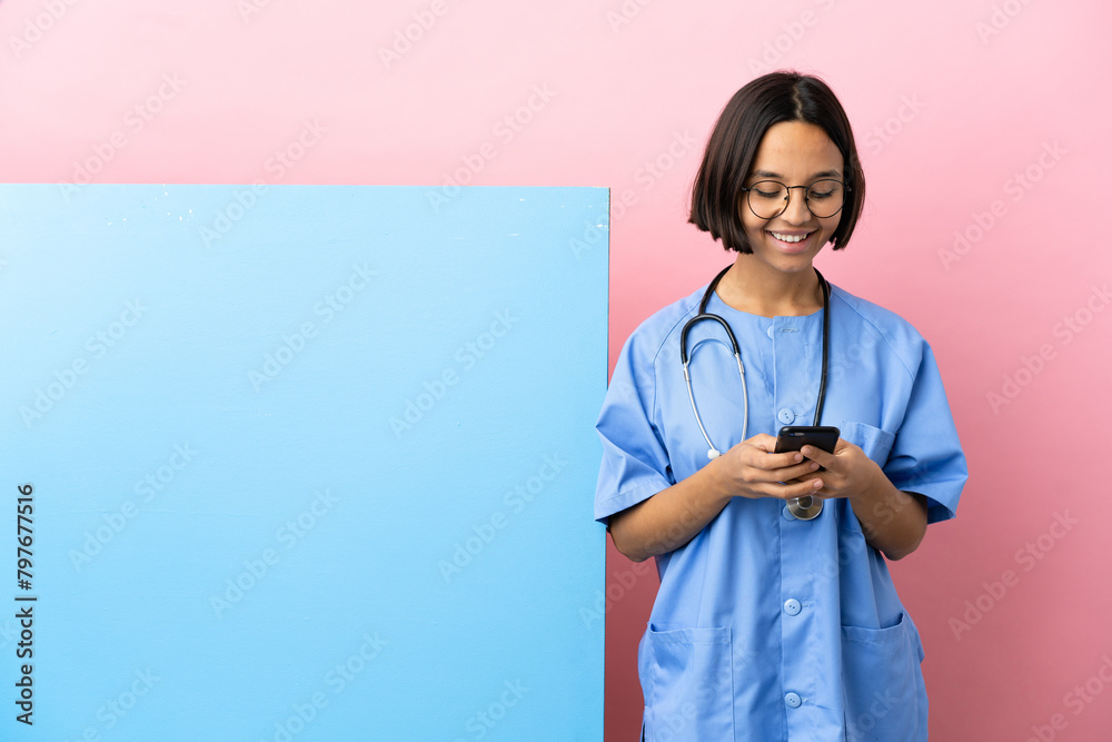 Young mixed race surgeon woman with a big banner over isolated background sending a message with the mobile Young mixed race surgeon woman with a big banner over isolated background sending a message with the mobile