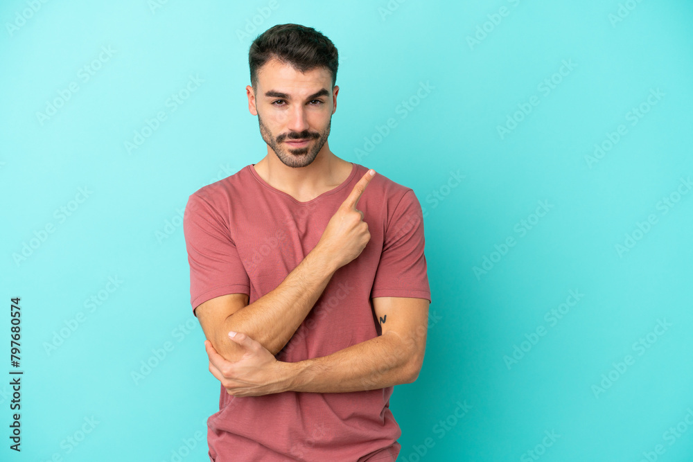 Young caucasian man isolated on blue background pointing to the side to present a product Young caucasian man isolated on blue background pointing to the side to present a product