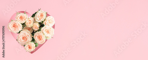 Festive light background with beautiful small roses. White roses and heart frame on pastel pink background. Mother's day, Valentines Day, wedding. Banner