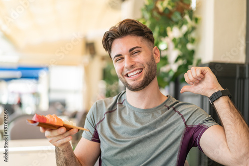 Young handsome man holding sashimi at outdoors proud and self-satisfied photo