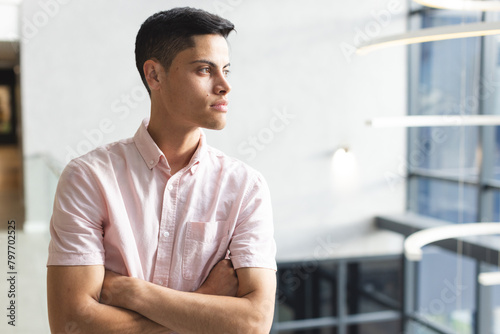 A young biracial man with dark hair gazes thoughtfully in a modern office photo