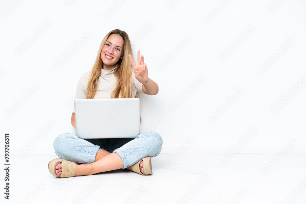 Young woman with laptop sitting on the floor isolated on white background happy and counting three with fingers Young woman with laptop sitting on the floor isolated on white background happy and counting three with fingers