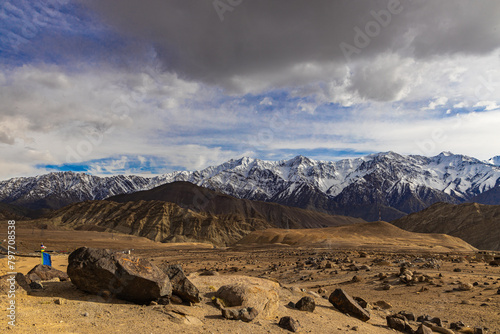 A wide-angle view of the snow covered mountain ranges with dark clouds in the horizon