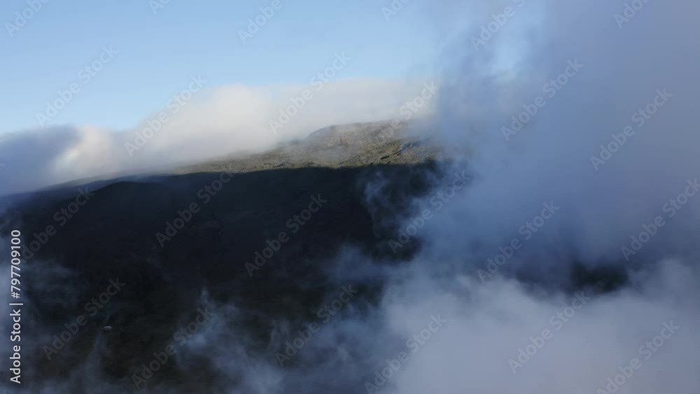 Thick fluffy white clouds cast dark shadows on tropical island slopes, aerial Thick fluffy white clouds cast dark shadows on tropical island slopes, aerial
