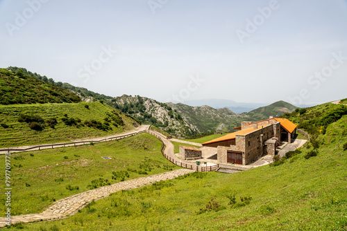 A small house sits on a hillside in a grassy field Enol lakes in covadonga asturias