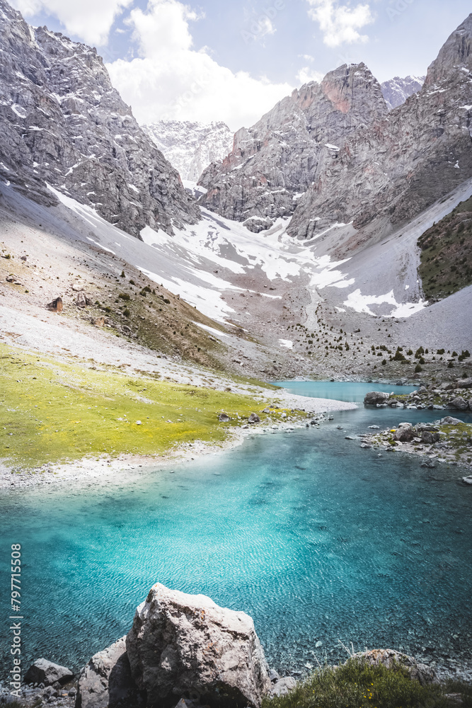 Mountain panorama, landscape with rocky peaks and blue turquoise lake Ziyorat in the Fan Mountains in Tajikistan, on a sunny summer day