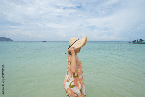 Happy Asian woman, a sexy Thai lady, relaxing and enjoying at turquoise sea near Phuket beach in summer during travel holidays vacation trip outdoors at natural ocean or island at noon, Thailand.