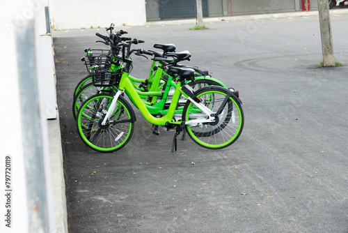 A row of green bicycles renting app are parked on the side of a road photo