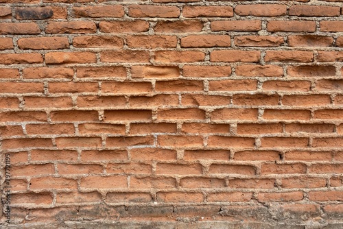 A brick wall with a rough texture and a few holes
