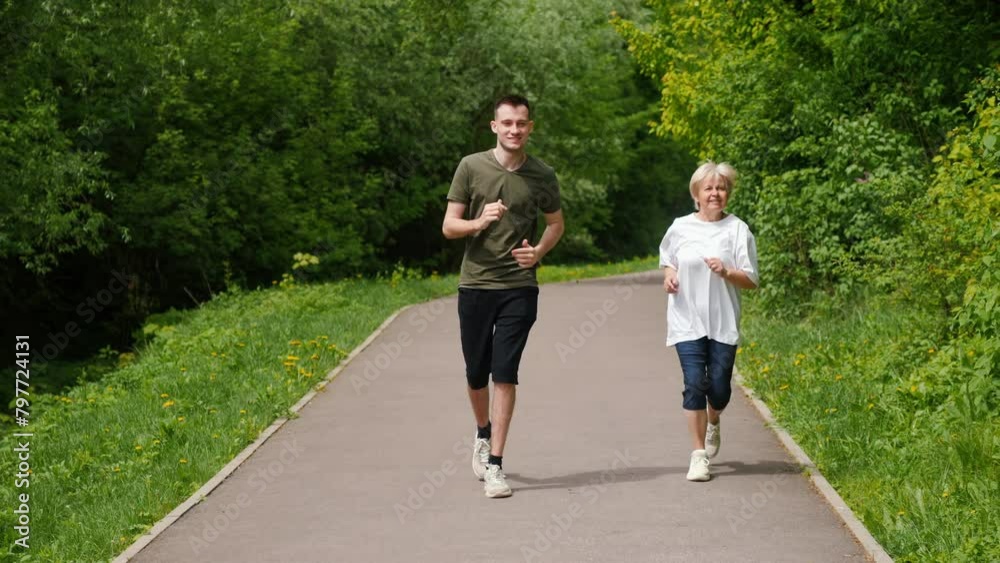 An elderly woman with a young man jogging in the park. Active seniors concept An elderly woman with a young man jogging in the park. Active seniors concept