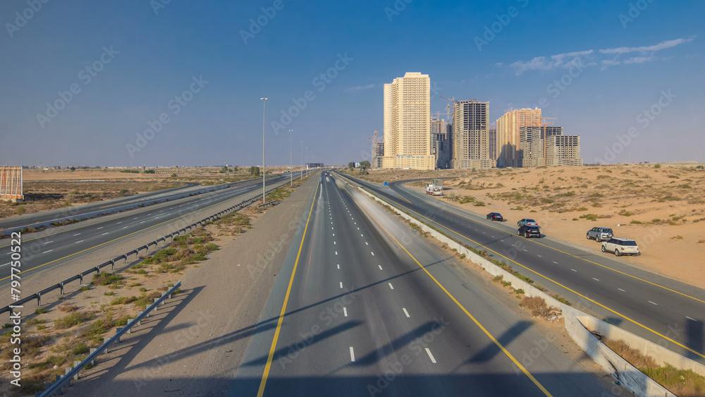 Highway roads with traffic timelapse in a big city from Ajman to Dubai before sunset. Transportation concept.