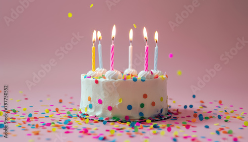 festive birthday cake with colorful candles and confetti on pink background
