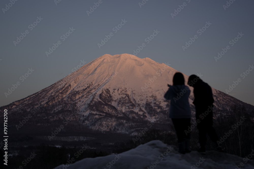 Silhouette of two individuals gazing at snowy Mount Yotei in Niseko, Japan.