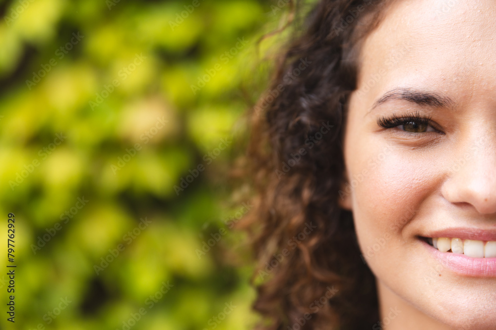 A young Caucasian woman with curly hair, smiling outdoors, copy space