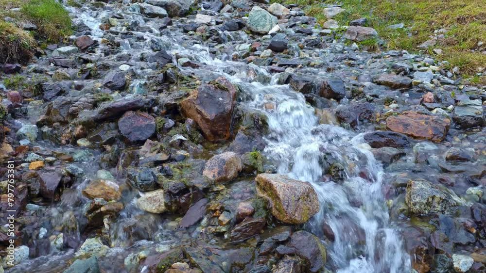 small mountain creek running down toward a camera between round rocks at summer day time, closeup with selective focus small mountain creek running down toward a camera between round rocks at summer day time, closeup with selective focus
