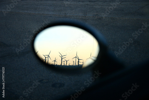 Wind turbines reflected in a car's rearview mirror at dusk.