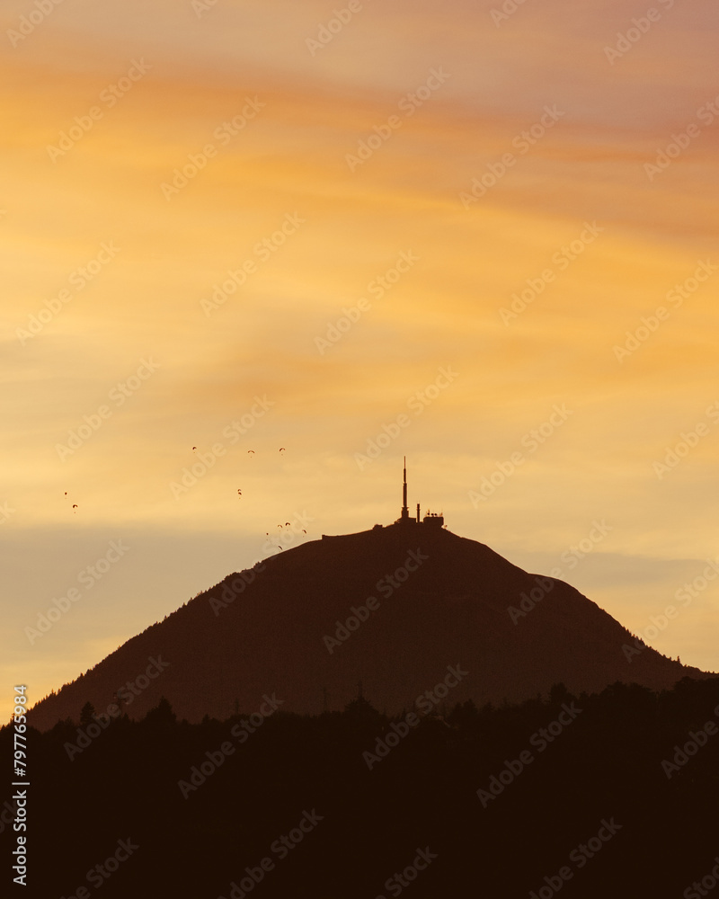 Sunset over the Puy de Dome in Chinese shadow with paragliders enjoying the last light.