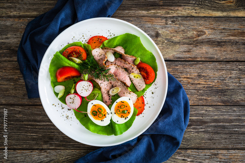 Tasty salad - roasted beef loin boiled eggs and fresh vegetables on wooden table
 photo