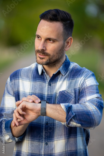 Handsome man looking at wristwatch outdoor photo