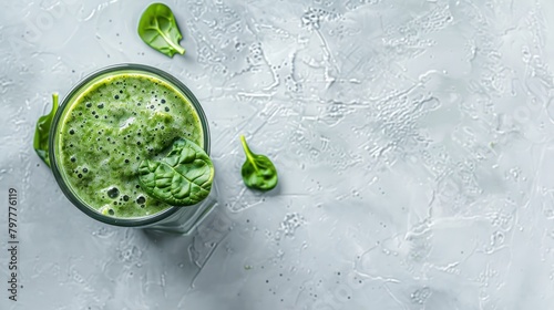 Detox spinach smoothie in a tall glass on white slate, stone or concrete background. Top view with copy space.