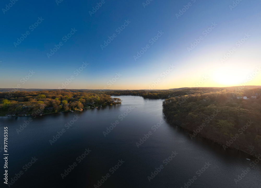 Experience a tranquil escape with these serene drone views of White Meadow Lake, New Jersey. The warm hues of sunrise and sunset cast a golden glow over the placid waters, highlighting the community's