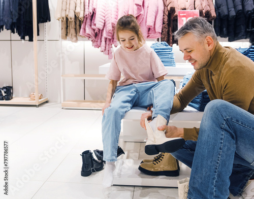 Father Assists Young Daughter in Trying On Shoes at Clothing Store