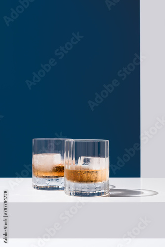 Dos vasos de whisky escocés con hielo sobre un fondo azul	 photo
