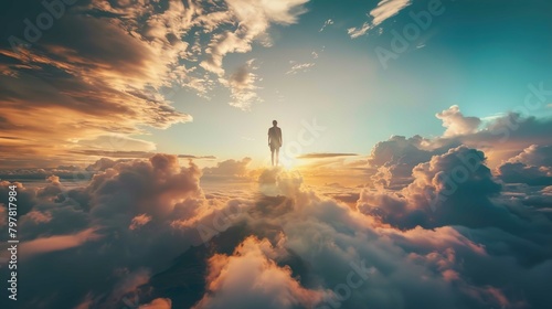A person stands on a peak, high above the clouds, with the vast sky above and around them. The clouds are thick and fluffy, glowing with shades of orange and yellow from the sun setting or rising in t photo
