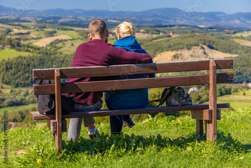 A woman and a man sit hugged on a bench. © Jacek